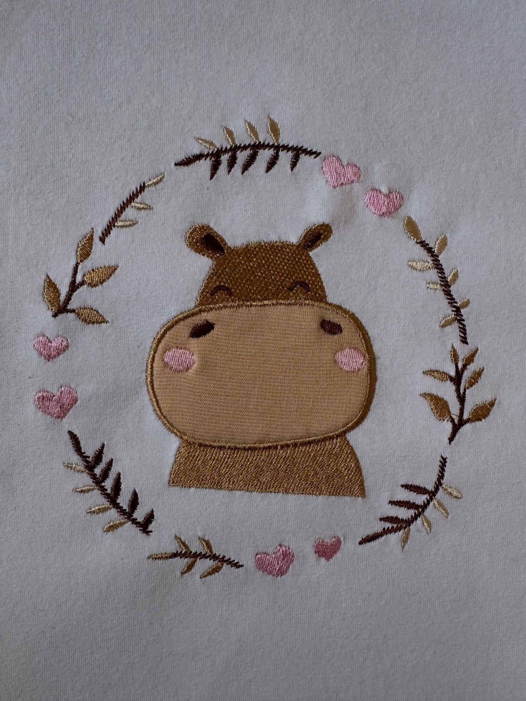 Machine embroidery design with a playful hippopotamus applique surrounded by curving branches in a real